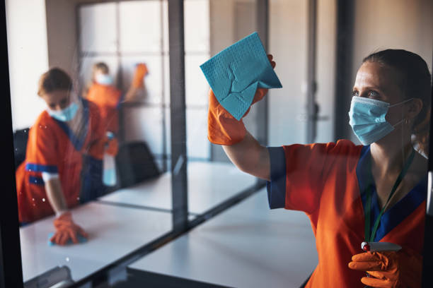Three woman sweeping an office area.